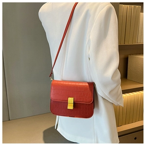 Vista detallada del bolso cuadrado rojo con relieve de cocodrilo y cierre dorado elegante