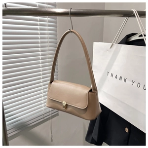 Detail of light khaki baguette bag hanging with a gold metal buckle closure