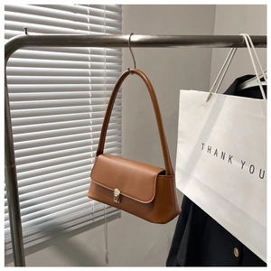 Detailed close-up of brown leather underarm bag with vintage gold metal buckle