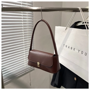 Detail shot of the dark brown leather shoulder bag with gold metal latch and smooth texture