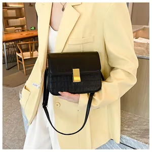 Detalle de bolso bandolera negro de piel PU con efecto cocodrilo y cierre metálico dorado
