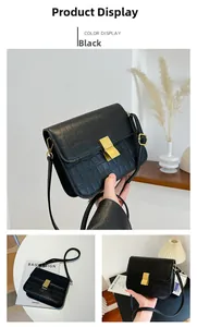 Detalle de bolso bandolera negro con relieve de cocodrilo y hebilla metálica dorada fina