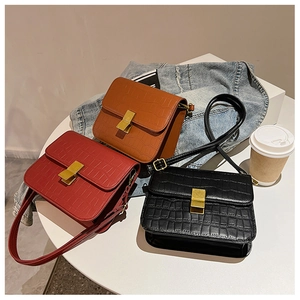 Detalle de bolsos bandolera cuadrados con diseño de cocodrilo y cierres dorados en tres colores