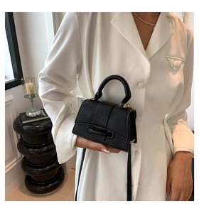 Detail of black pebbled leather mini crossbody bag with unique ring buckle and top handle