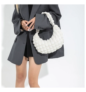 Détail de la texture matelassée blanche d'un sac demi-lune avec bandoulière plissée élégante