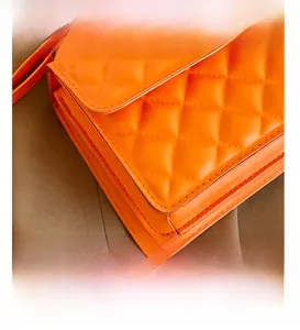 Detail view of orange quilted faux leather crossbody bag with multi-layer side gussets