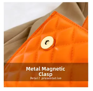 Detail of bright orange crossbody bag showing quilted texture and gold magnetic clasp