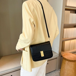 Bolso bandolera negro con diseño de cocodrilo y cierre dorado usado por modelo