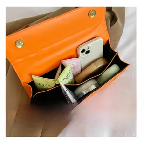 Detail presentation showing internal multi-compartments of orange square leather bag