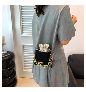 Detail of black woven crossbody bag with white drawstring liner and gold chain strap