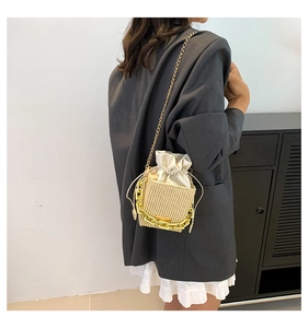 Detail of woven bucket bag featuring drawstring closure and vibrant yellow chain handle
