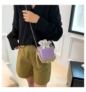 Detail of purple woven mini bag with thick gold chain and drawstring interior