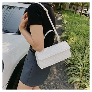 Outdoor street style view of a white quilted crossbody bag with stylish rhombic pattern