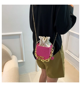 Detailed view of fuchsia woven bucket bag with gold chain strap and drawstring lining