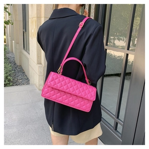 Outdoor shot showing the bright pink quilted crossbody bag with gold hardware on a model