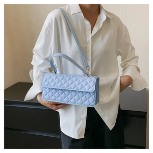 Side view of light blue quilted crossbody bag with gold hardware on a female model