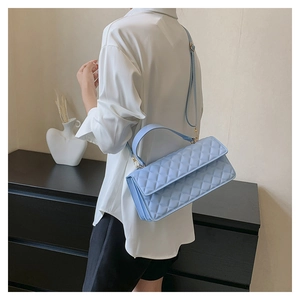 Detail view of light blue quilted crossbody bag with golden metal hardware and handle