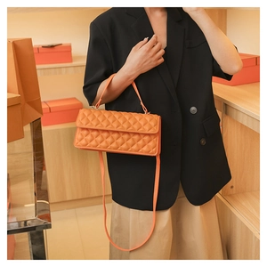 Detail of orange quilted crossbody bag with flap and elegant chain shoulder strap