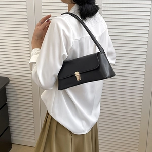Classic black baguette shoulder bag with gold clasp shown on a model in a stylish outfit