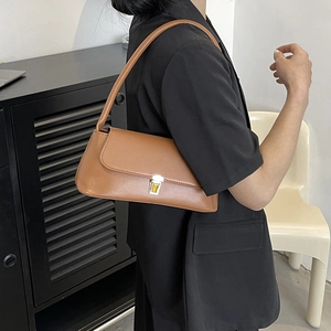 Classic brown leather baguette bag with silver buckle worn by a model in casual style