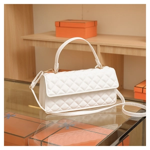 Close-up of white quilted handbag with gold hardware on a glass display stand