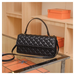Detail of black quilted leather square handbag with golden hardware and top handle