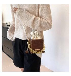 Close-up of brown plaid bucket bag with gold chain and white drawstring liner