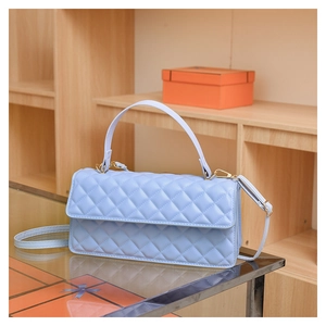 Detailed close-up of light blue quilted crossbody bag with elegant gold hardware and texture