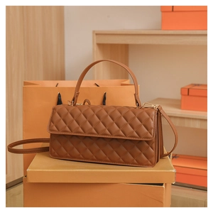 Detailed view of brown quilted leather bag with gold hardware on orange box