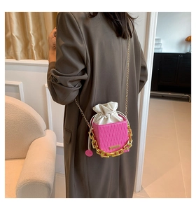 Detailed view of pink pleated bucket bag with gold chain and white inner drawstring