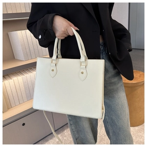 Close-up of beige Saffiano tote bag showing durable leather texture and gold hardware