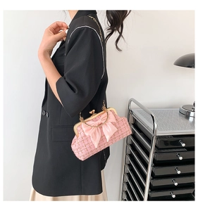 Détail du sac en tweed rose avec nœud en soie et chaîne dorée porté par un mannequin