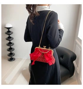 Gros plan du sac en tweed rouge avec grand nœud en satin et bandoulière dorée