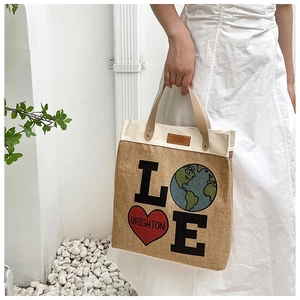 Detail of jute and canvas tote bag with LOVE graphics and leather handles outdoors