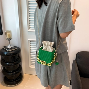Green woven bucket bag with chunky gold chain and inner drawstring pouch