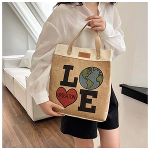 Detail view of woven tote bag with LOVE print on model in a cozy home setting