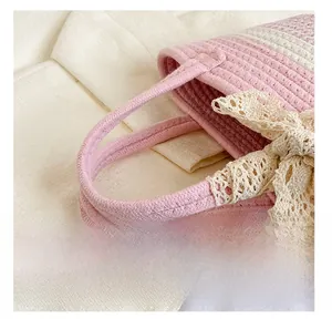 Dettaglio della borsa a secchiello intrecciata rosa e bianca con fiocco in pizzo