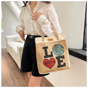Detail of canvas tote bag with brown leather handles and Brighton style heart graphic