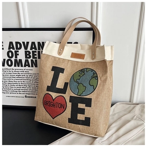 Detailed close-up of jute tote bag with LOVE logo and leather handle texture