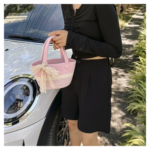 Dettaglio della borsa a cesto intrecciata rosa e bianca con fiocco in pizzo beige