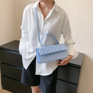 Light blue quilted crossbody bag with top handle worn by a model in white shirt