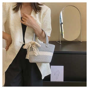 Dettaglio della borsa tote all'uncinetto a righe fatta a mano con un delicato fiocco in pizzo crema