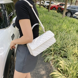 Elegant white quilted crossbody bag with gold hardware and top handle shown on model
