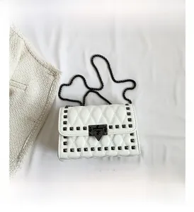 Detail view of white quilted leather crossbody bag featuring black pyramid stud accents