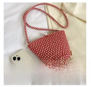 Détail du sac seau tissé rouge et blanc avec fermoir perle et téléphone pour la taille