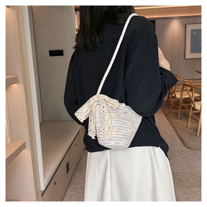 Dettaglio borsa tessuta colorata con grande fiocco in pizzo ed elegante perla bianca