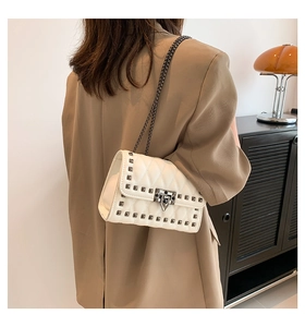 Rear view of a model wearing a white quilted bag with studs and a metal chain strap