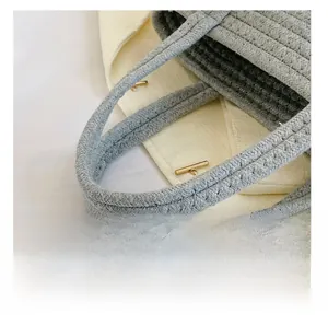 Close-up of thick woven handles on a gray straw bag with premium texture and detail