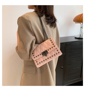 Pink quilted crossbody bag with metal studs and chain strap shown on model's shoulder