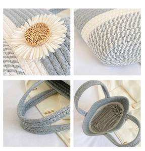 Detail of hand-woven straw tote bag showing blue-white stripes and large daisy flower